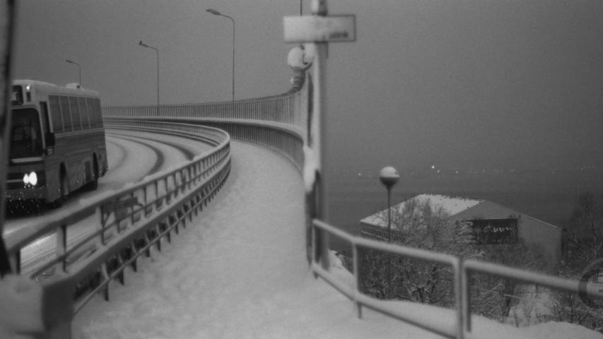 bus driving over bridge during snow fall