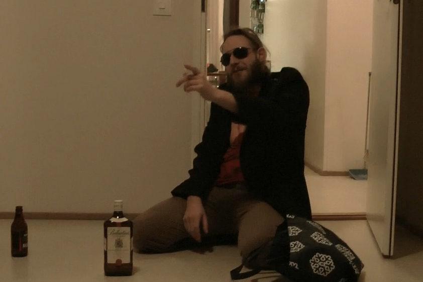 person wearing sun glasses in front of whiskey bottle